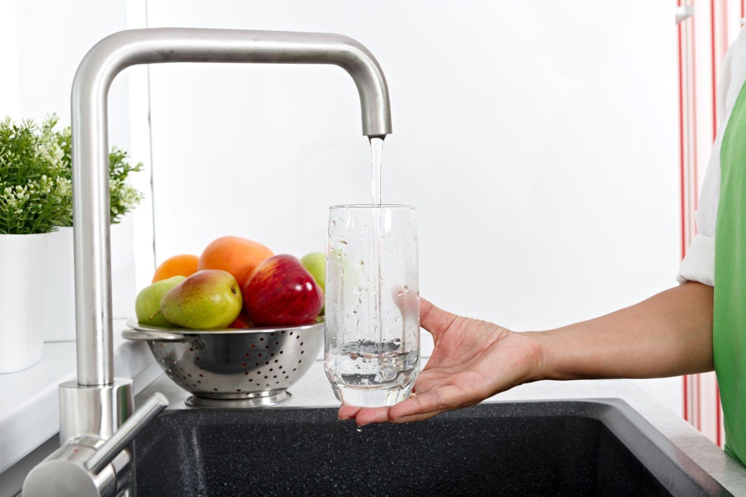 Girl filled with water. Tap filling a Glass of Water in Kitchen.